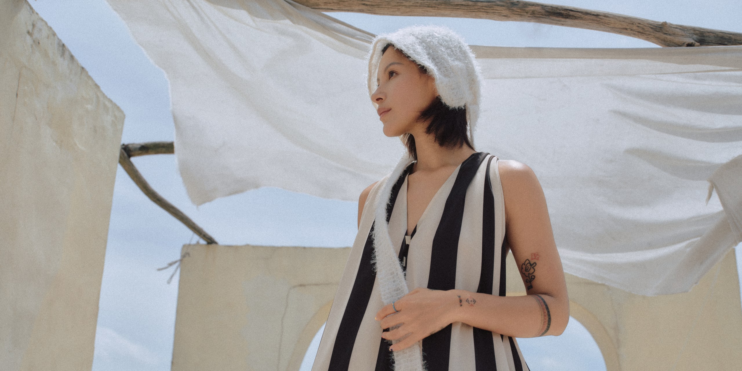 Model wearing an ERRIESE hat in an outdoor architectural setting